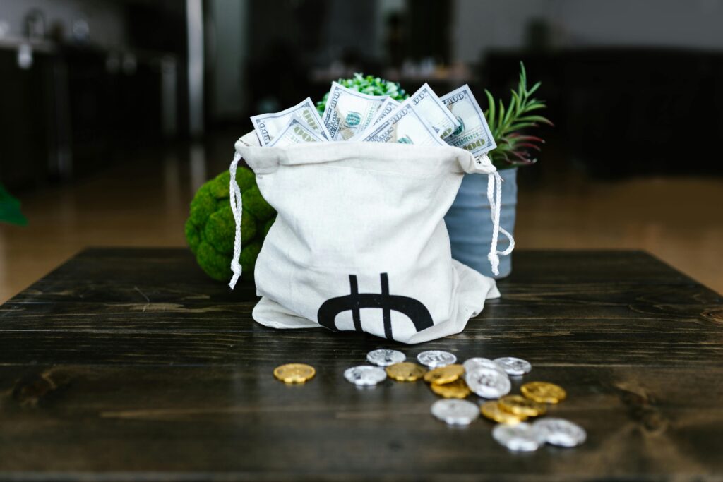 A tote bag filled with cash and coins symbolizing cryptocurrency wealth on a wooden table.